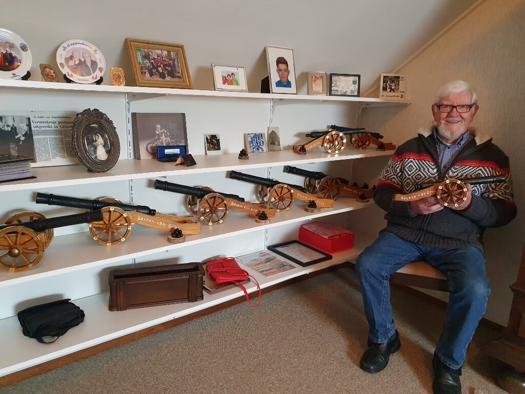 Henk glimmend van trots tussen foto's van dierbaren en een deel van zijn kanonnen. Foto: Henri Walterbos