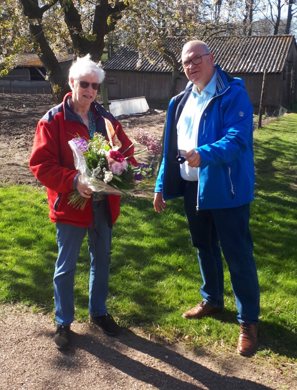 Gerrie Nijenhuis, tien jaar vrijwilligster van de Zonnebloem, ontvangt van voorzitter Henk Hovenga een speld en bloemen. Foto: PR