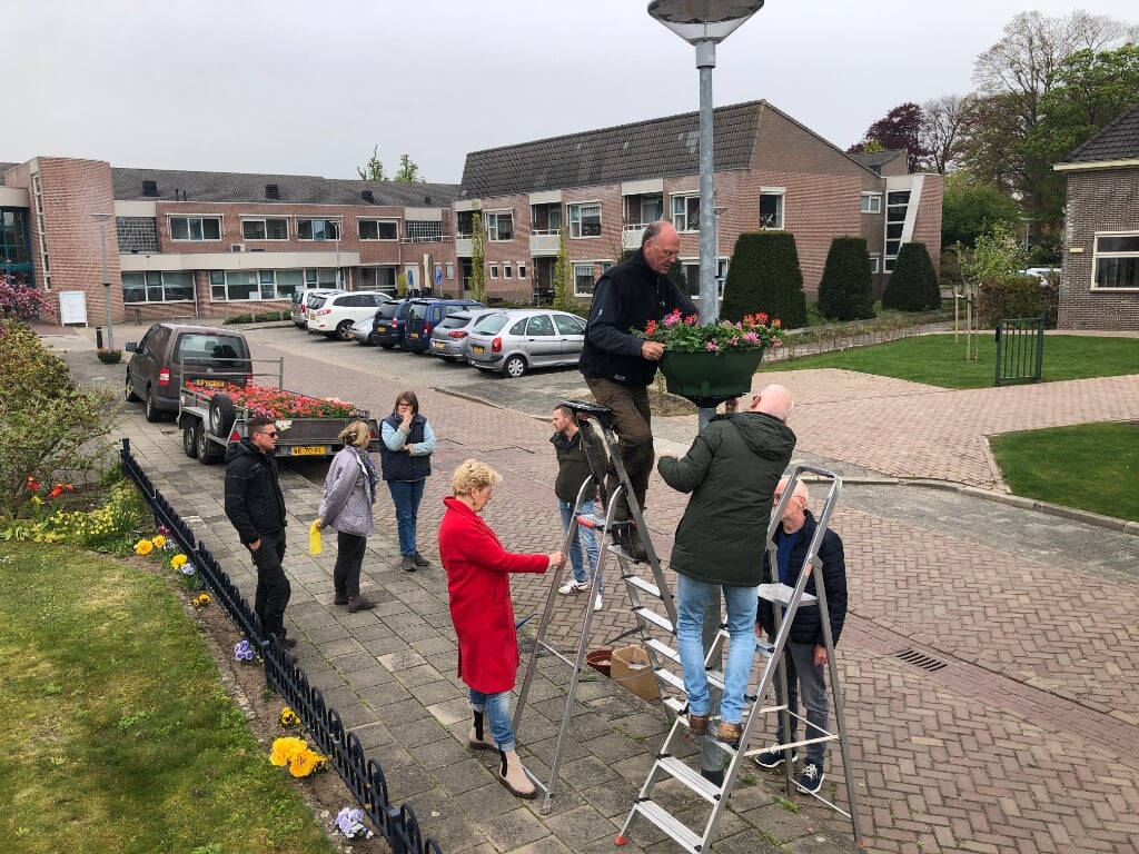 Vrijwilligers gaan de trapjes op om de bloembakken te bevestigen. Foto: Geert Postma