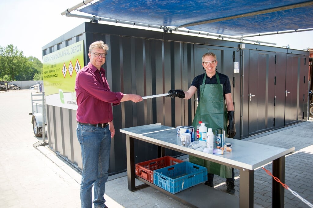 Wethouder Henk van Zeijts (links) opende het innamepunt voor klein chemisch afval op het Recycleplein in Lochem. Medewerker Ronald Colenbrander (rechts) neemt het klein chemisch afval in ontvangst. Foto: Yke Ruessink