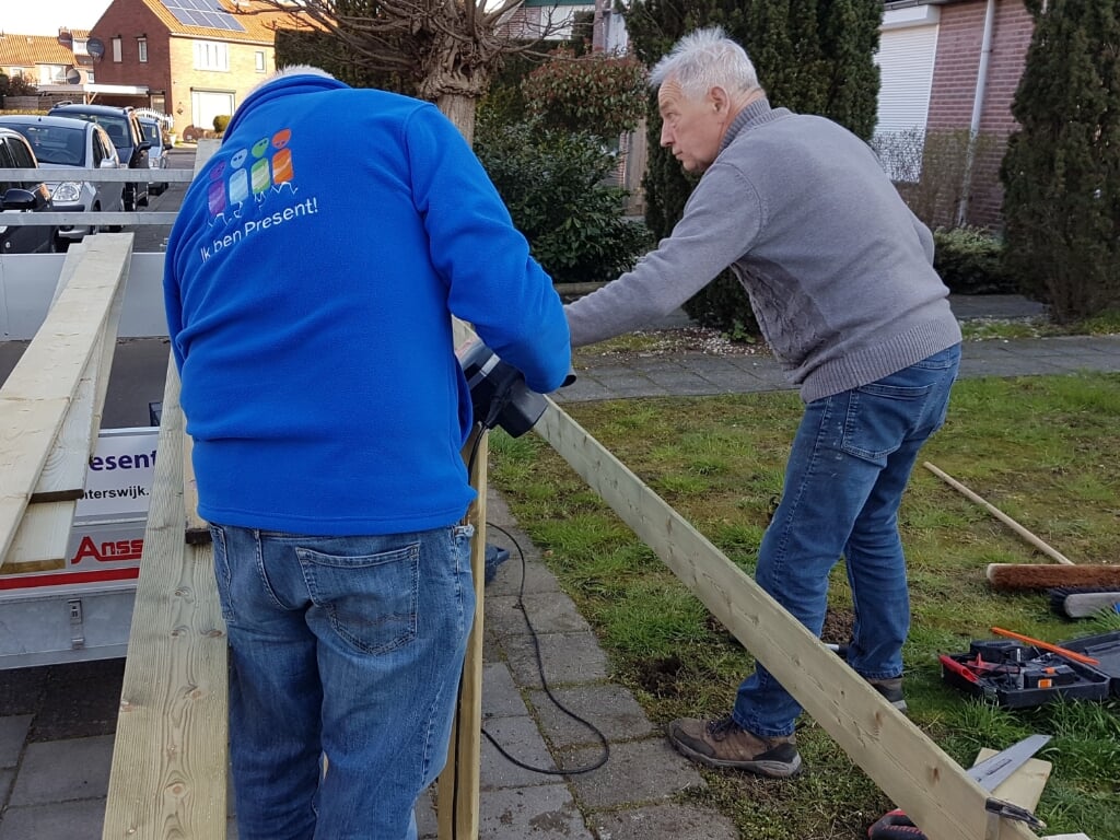 Twee vrijwilligers maken een hek om een voortuin