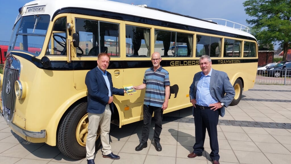 Frank van Setten ziet toe hoe Peter van der Meer (links) aan Henk Beskers het eerste exemplaar van het boek ‘Met de GTW-bus onderweg’ overhandigt. Foto: Han van de Laar