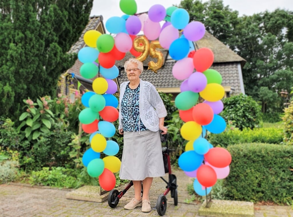 Op de verjaardagstaart van Gerda Gaijkhorst-Kornegoor staan 95 kaarsjes. De buurt zette haar in het zonnetje met een ballonenboog. Foto: Alice Rouwhorst