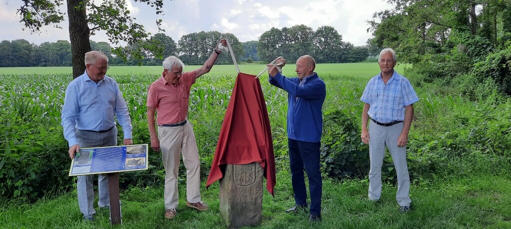Leo van Dijk en Willy Gelinck onthullen de grenssteen uit 1766. Links kijkt Dick Lammers toe en rechts staat Johan Baake. 