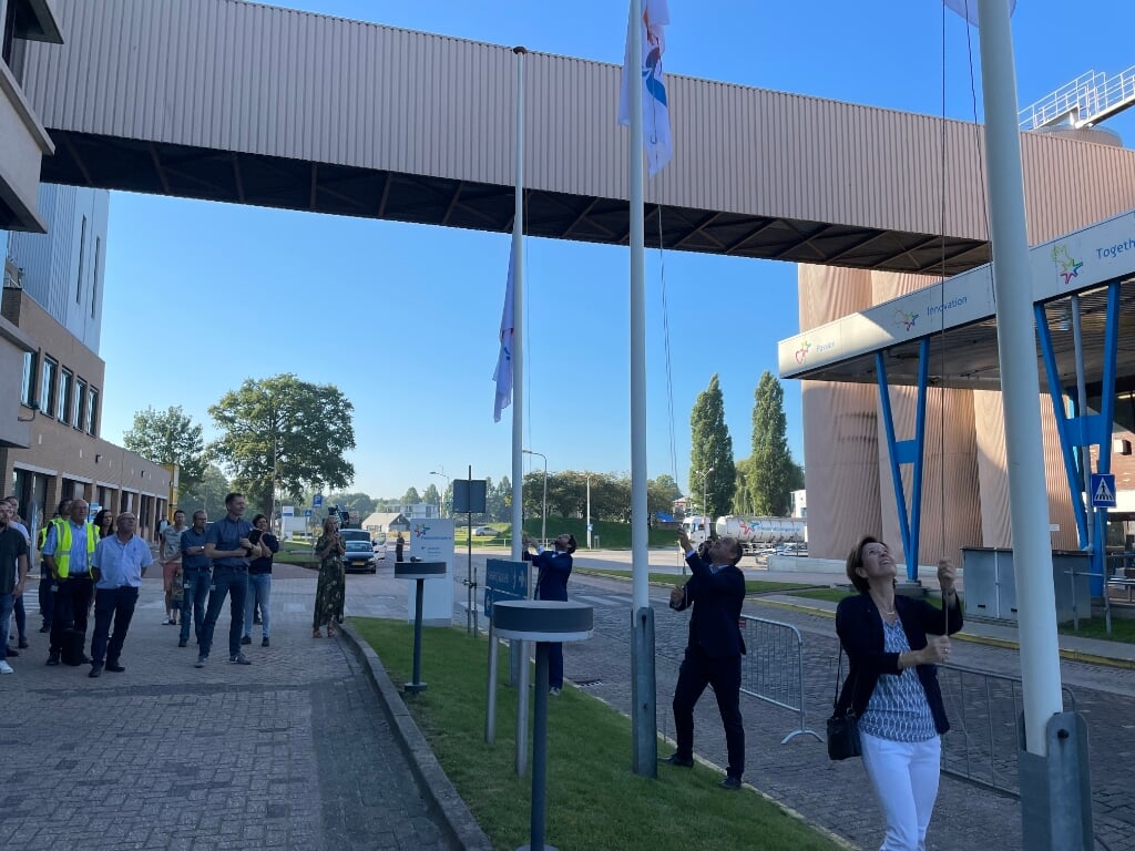De jubileumvlaggen van het 150-jarige FrieslandCampina worden gehesen voor (van voor naar achter) commissaris Sandra Addink, plantmanager Remco Nühn en burgemeester Sebastiaan van 't Erve. Foto: Henri Bruntink)
