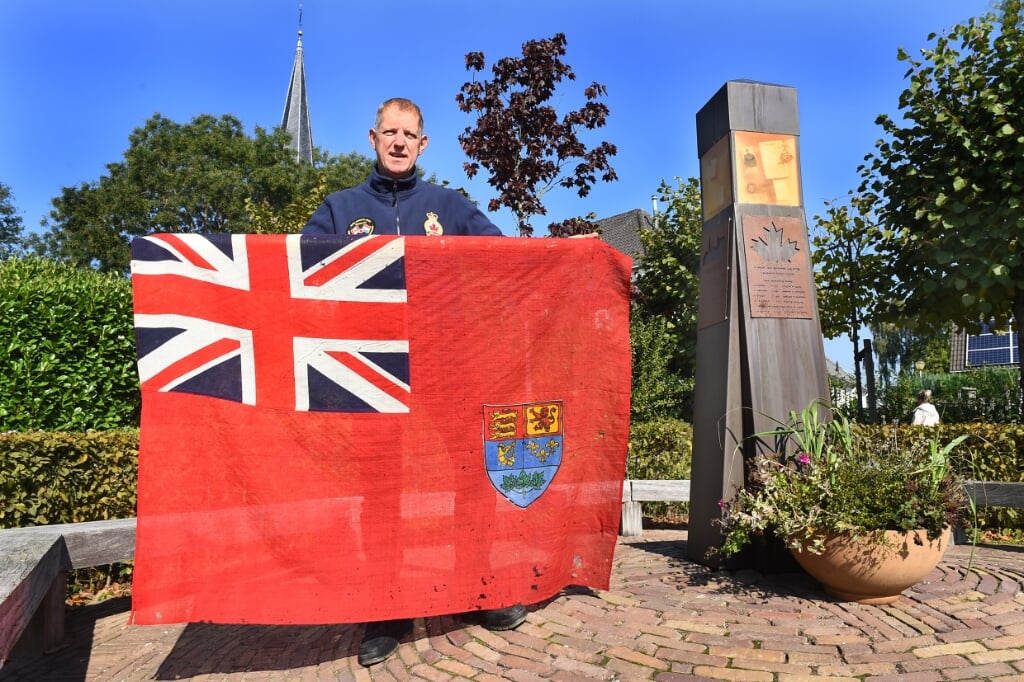 Mark van Aken met de unieke vlag bij het herdenkingsmonument in Etten. Foto: Roel Kleinpenning