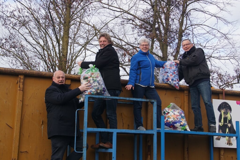 Wethouder Veldhuizen (links), burgemeester Anton Stapelkamp, Annie en Jan Gussinklo gooien zakken doppen in de container. Foto: Frank Vinkenvleugel
