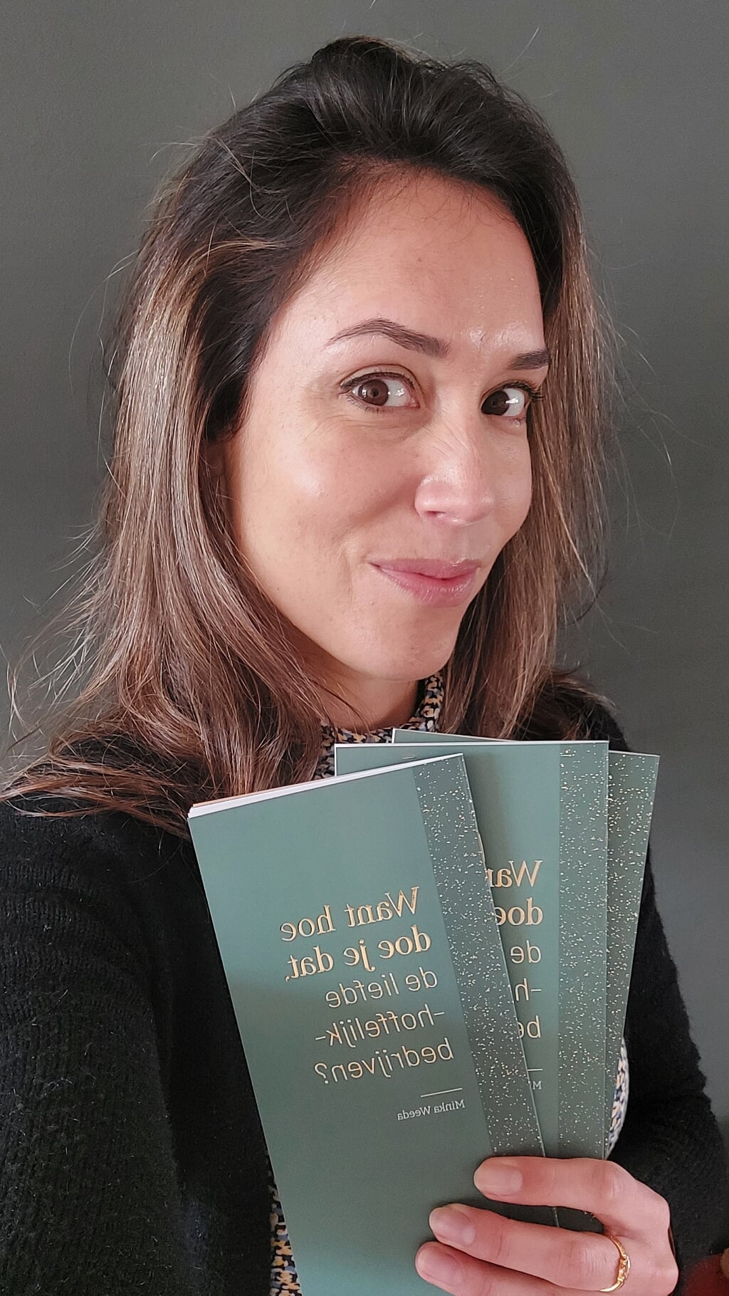 Minka Weeda toont de drie exemplaren van haar poëziedebuut die zij aan de winnaars van de lezersactie gaat opsturen. Eigen foto.