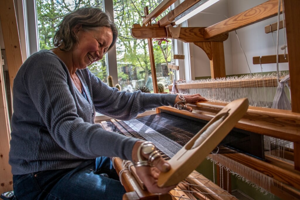 Koertien Minjon aan een van de weefgetouwen in haar atelier in Steenderen waar zij eigen stoffen maakt. Foto: Liesbeth Spaansen