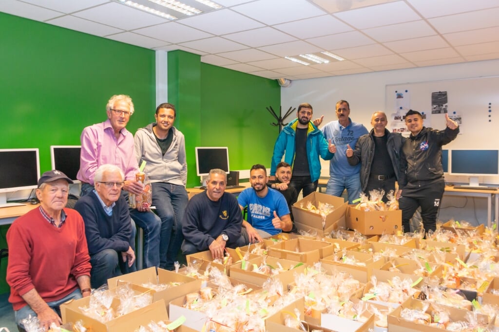 Vrijwilligers en vluchtelingen met dozen vol pakketjes. Foto: Henk Derksen