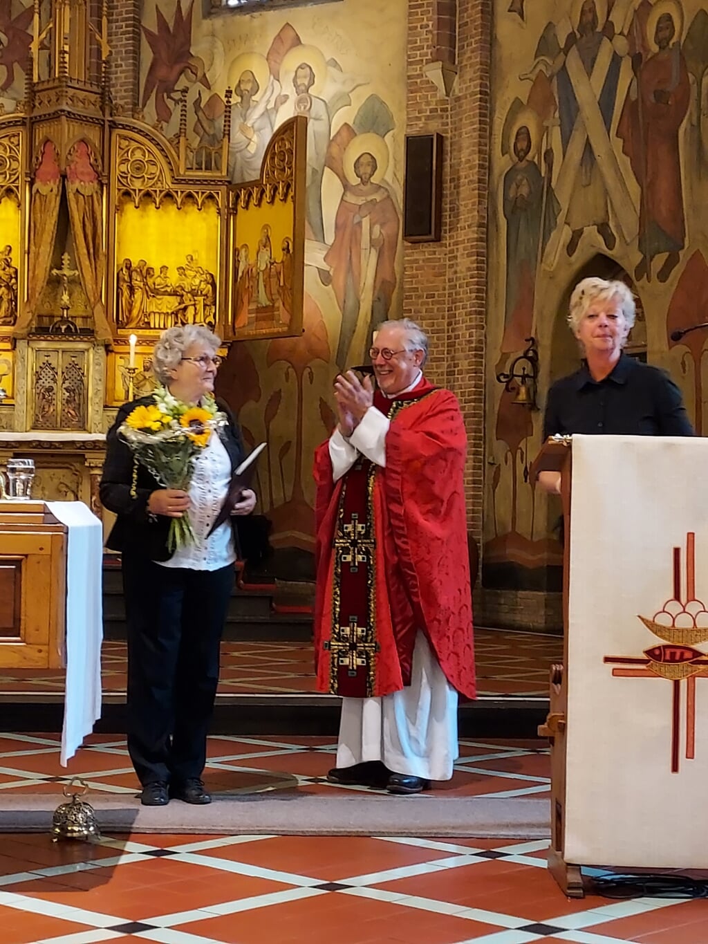 Willy Niesink krijgt voor haar werk in de kerk door pastoor Scheve de Willibrordplaquette uitgereikt tijdens haar afscheid. Foto: Ciska Gerritsen