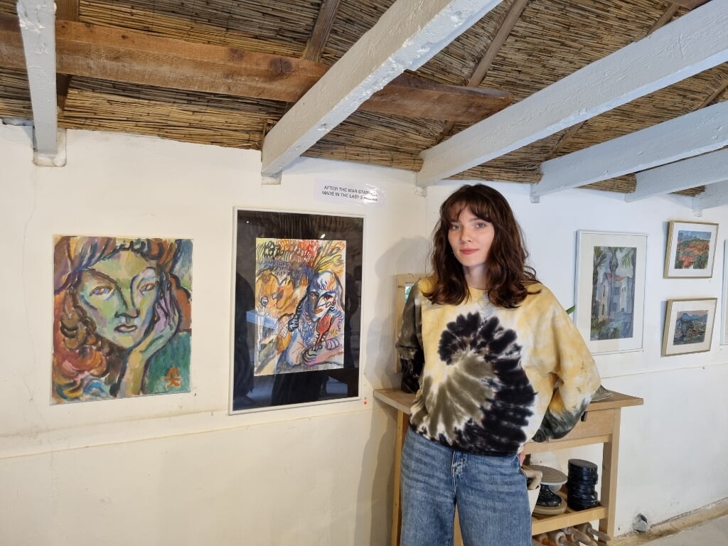 Kunstenaar Maria Kitaeva; links van haar de schilderijen voor de inval van de Russen en rechts haar zelfportretten na de inval. (Foto: Rob Weeber