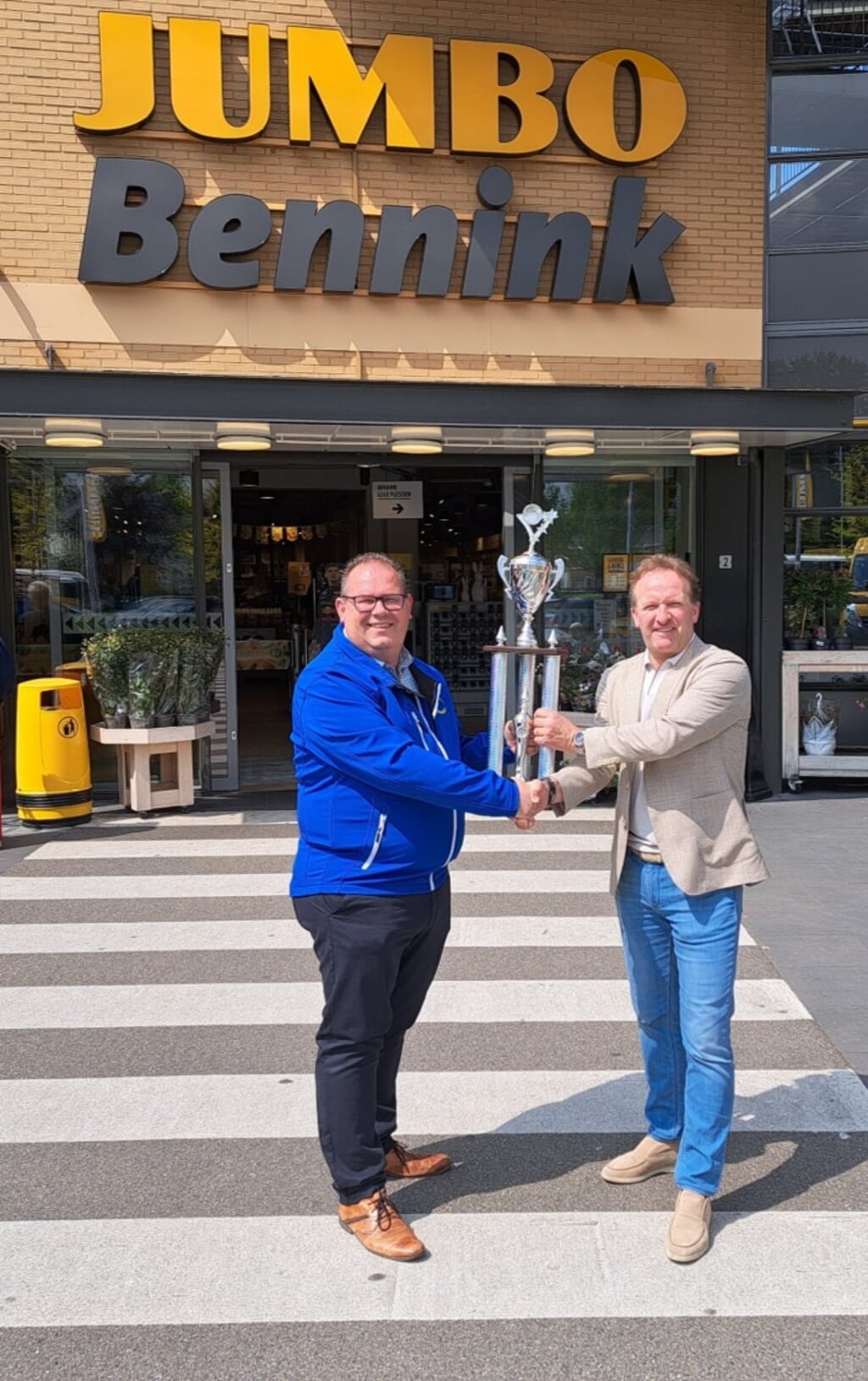 Voorzitter van het Open Achterhoeks Dweilorkesten Kampioenschap Frank Beurskens (links) neemt de nieuwe hoofdprijs in de Leutklasse in ontvangst uit handen van Pascal Bennink. Foto: PR
