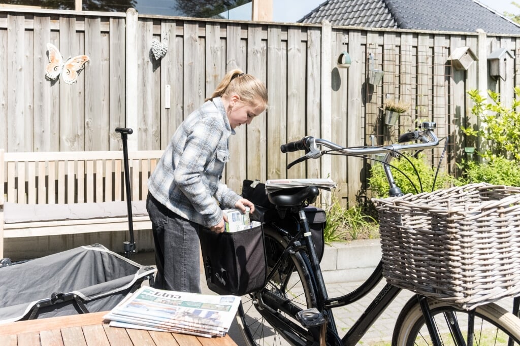 Nienke pakt een voorraadje kranten in de fietstas. Foto: Janette van Egten