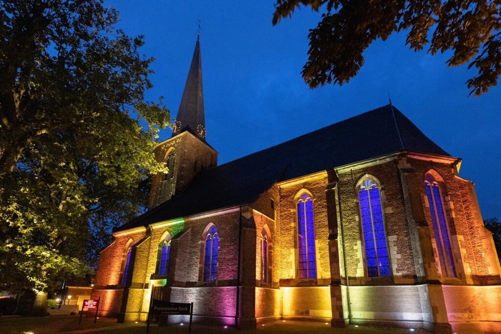 De in regenboogkleuren aangelichte Mattheus-kerk is niet te missen voor wie het dorp binnenrijdt bij het invallen van de nacht. Foto: PR