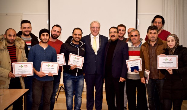 De statushouders met burgemeester Romeyn in het midden. Rechts van de burgemeester de heer Aziz Azizi, hij heeft dit project ontwikkeld.
Foto: Stip Fotografie