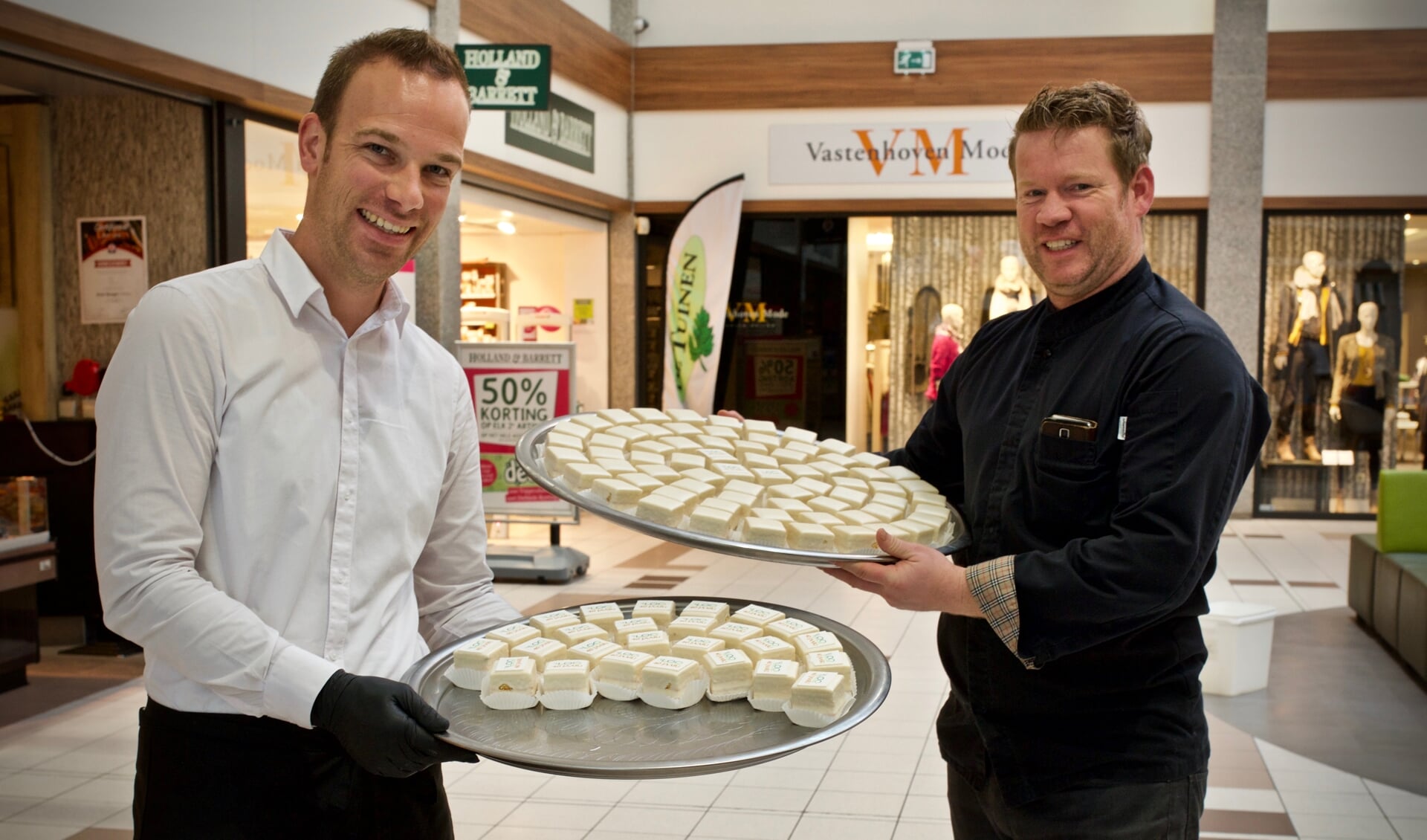 Dennis van Line-Up Events en John Hoetjes van Bakkerij Kees Zoon delen gebakjes uit aan het winkelend publiek.