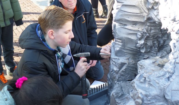 Op de foto Jona Mulder tijdens het inkloppen van zijn naam op het standbeeld.