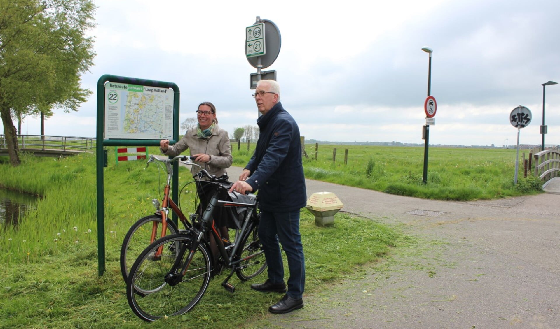De wethouders De Vink (links) en Rood staan even stil op de hoek Heemstederweg / Uitgeesterweg bij een van de knooppunten van het Fietsroutenetwerk dat ook door Castricum en Uitgeest voert.