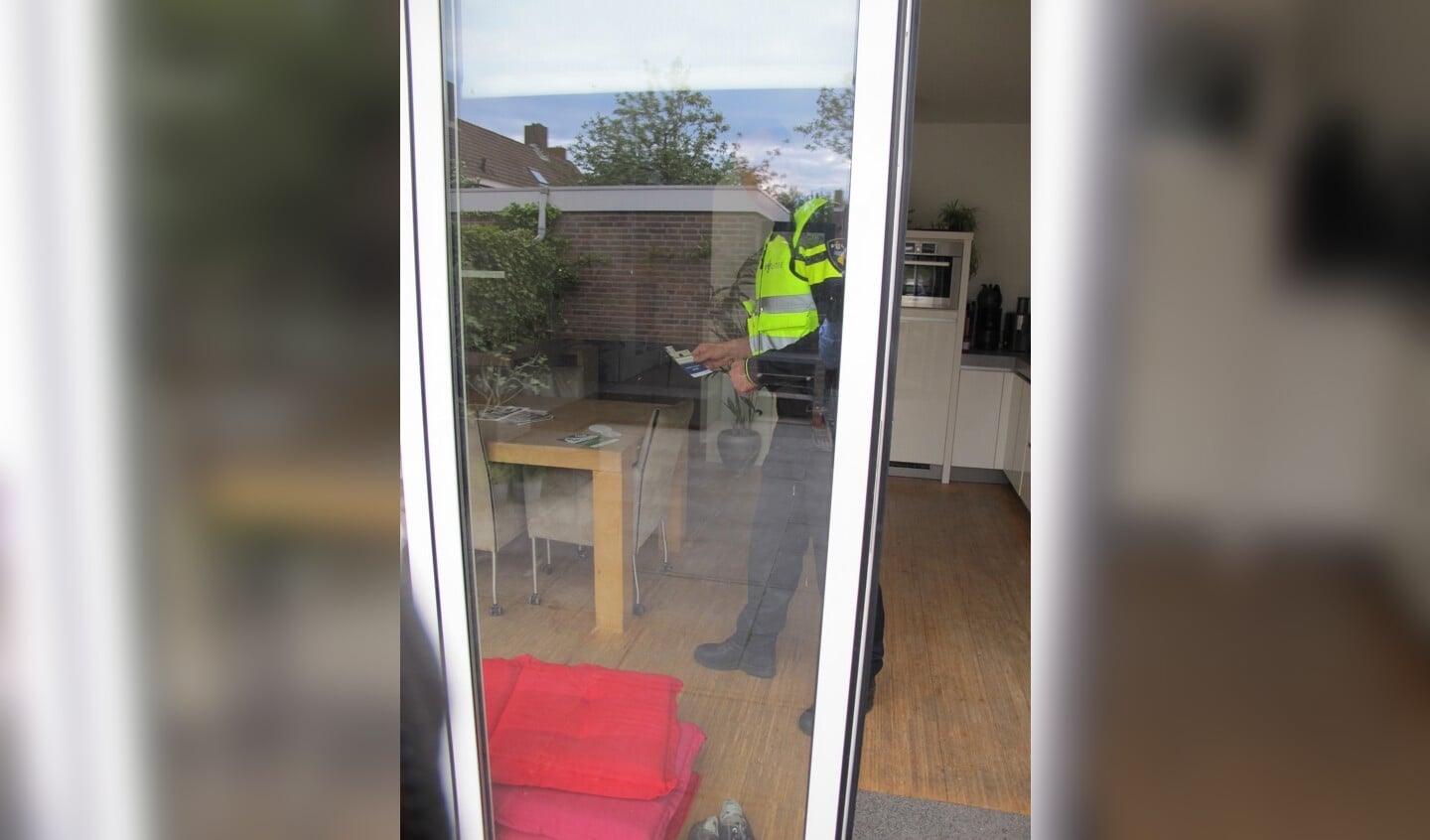 Een politieagent legt een ‘witte voetjes’-brochure in een woning waarvan de deur openstond. Bron: www.buurtpreventieheiloo.nl