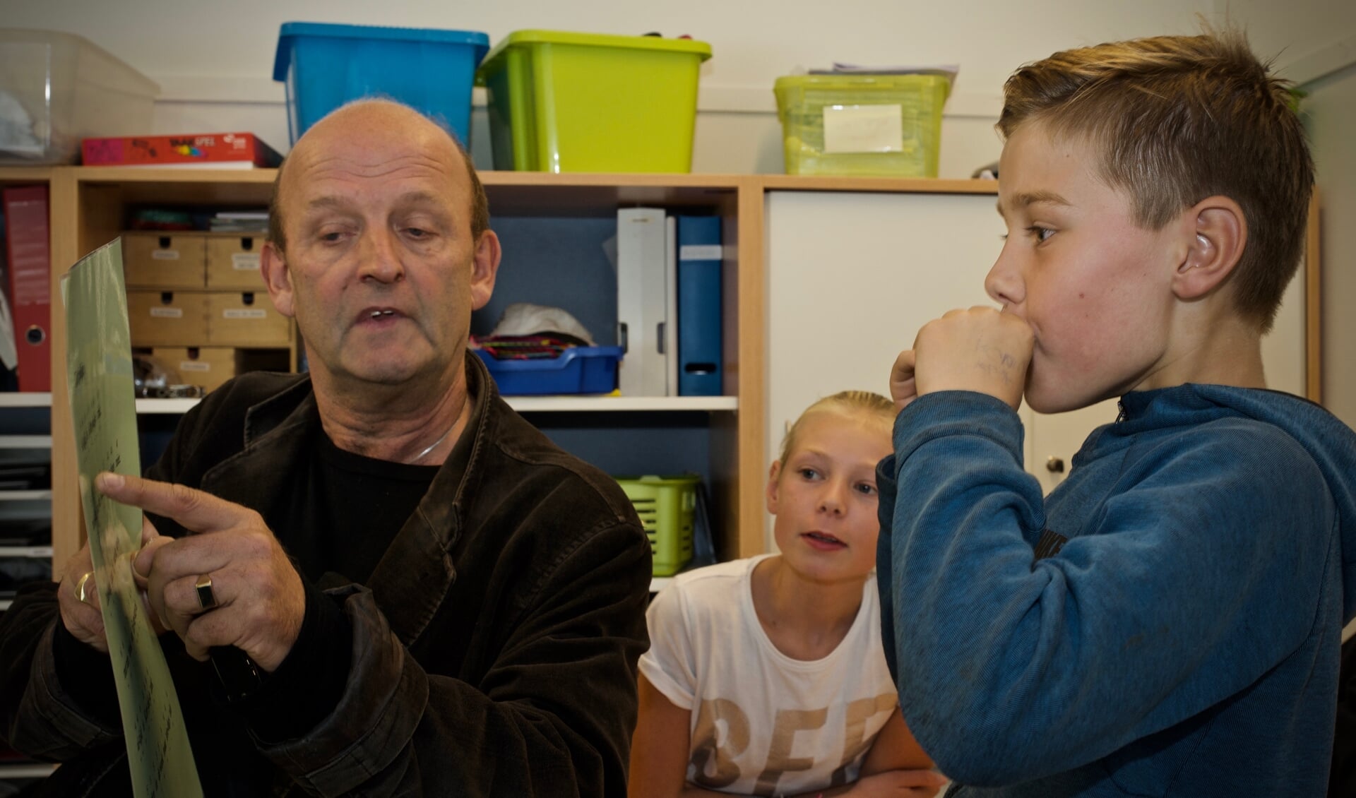 Eugène Vriend leert de leerlingen van de Paulusschool hoe je Kortjakje speelt op de mondharmonica.