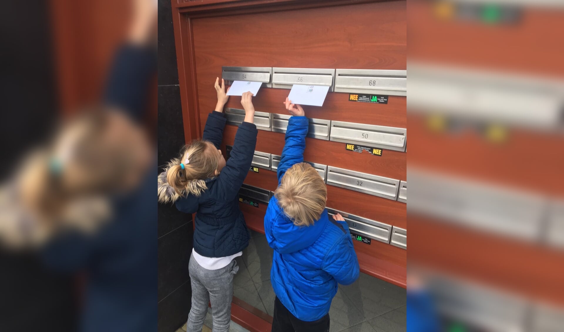Twee leerlingen bezorgen de kaarten in de brievenbus. 