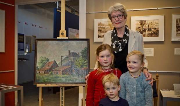 Jannie Baltus-Dekker met het gerestaureerde schilderij van haar vader. Voor Jannie Baltus-Dekker drie van haar vier kleinkinderen, Saar Ruigewaard, Poppy Baltus en Midas Baltus. Robin Langedijk was helaas verhinderd. 