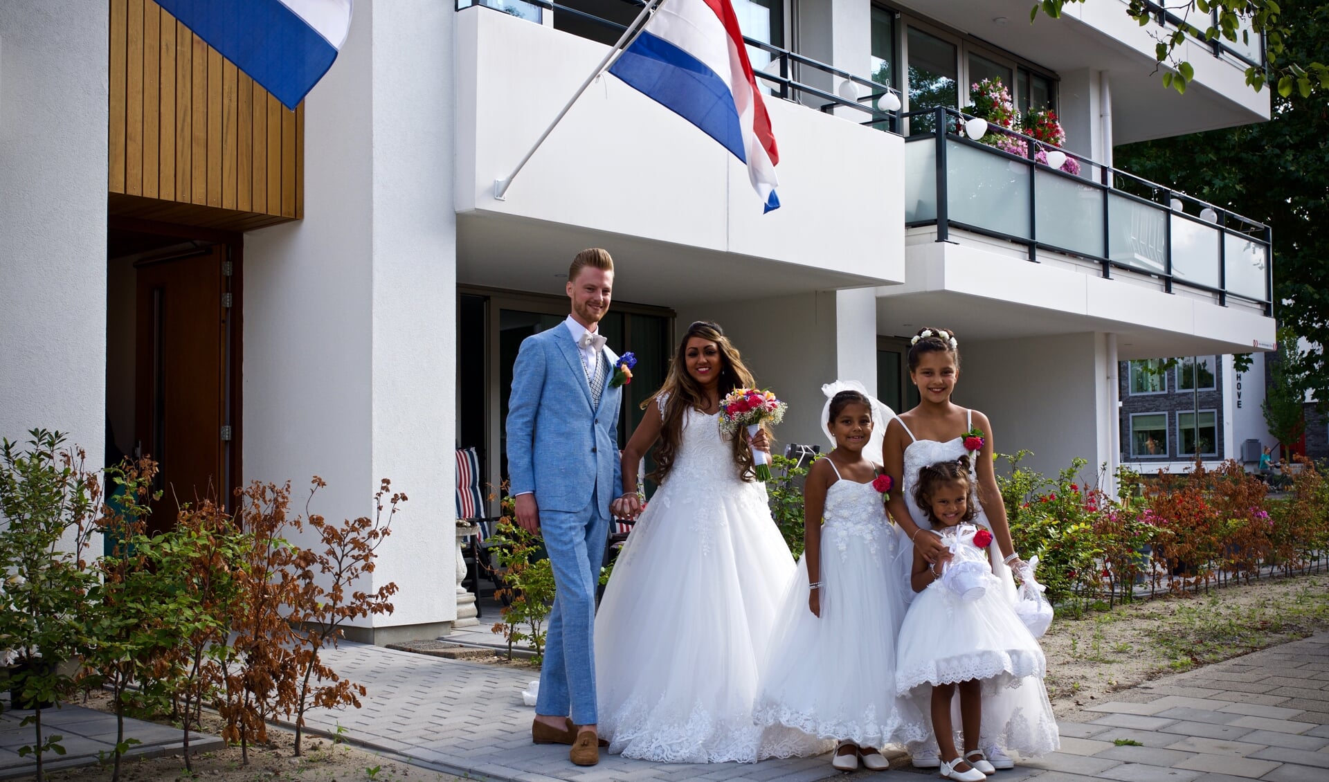 Martijn en Anisha voor het appartementencomplex 'Van Muyen' samen met de bruidsmeisjes Fabienne, Eline en Iselle.