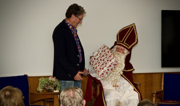 Samensteller van de tentoonstelling, Joop Tulp ontvangt van Sinterklaas een cadeautje.