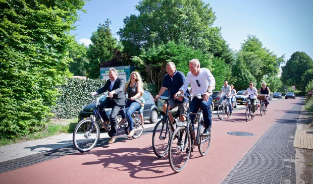 Wethouder Rob Opdam opent de fietsstraat door fietsend op de tandem de Hoogeweg op en neer te rijden. Achterop buurtbewoonster Wendy met zoontje Sky.