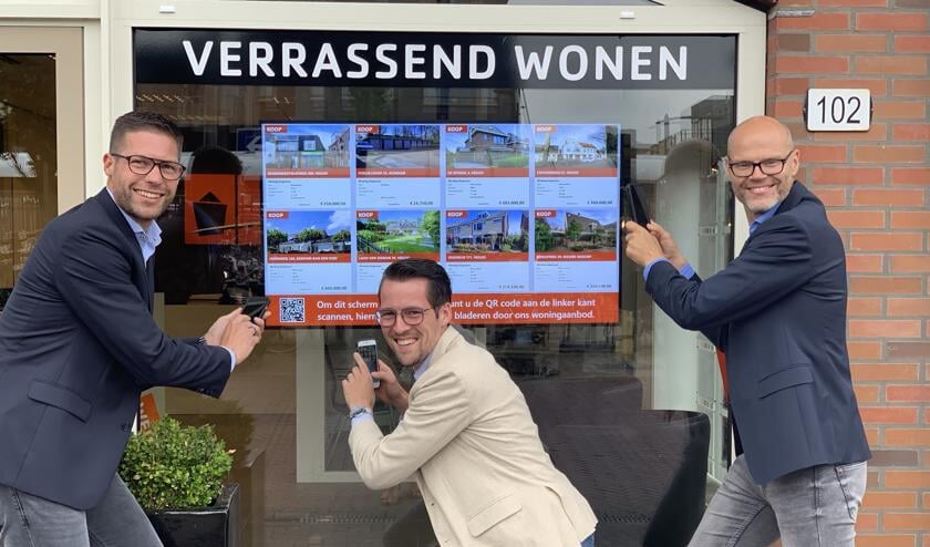 Bas, Jeffrey en Ronald nemen met hun eigen smartphone een 'virtueel kijkje' in en om de woningen via de flatscreen in de etalage.