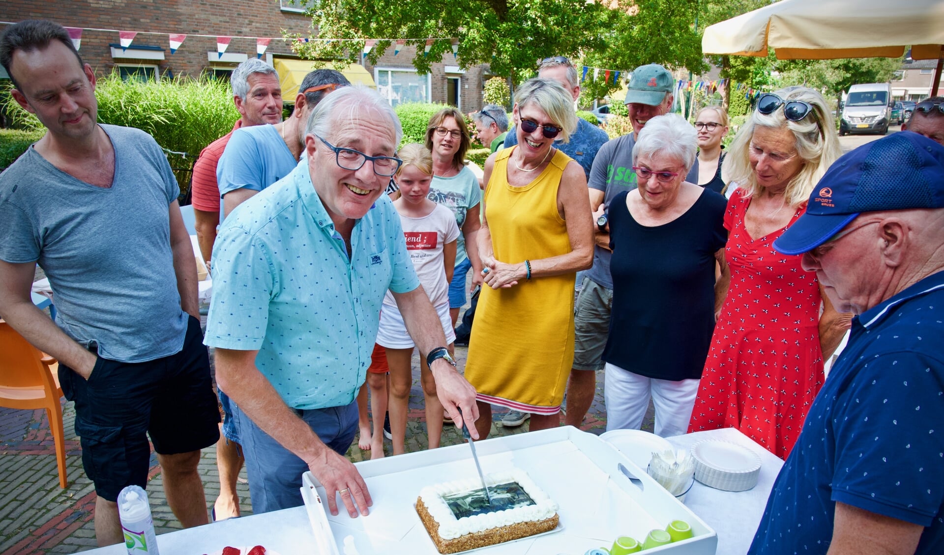 Burgemeester Hans Romeyn snijdt de speciale 'Het Bleekveld-taart' aan onder het toeziend oog van de bewoners.