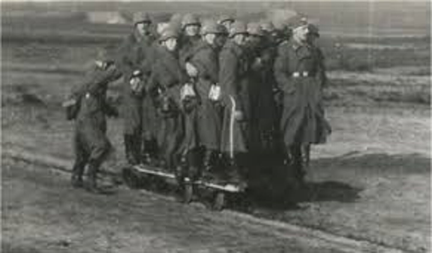 Duitse soldaten rijden mee met een platte lorrie.