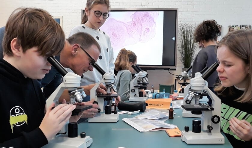 Leerlingen van basisschool Helmgras onderzoeken cellen onder de microscoop tijdens een bètaworkshop in samenwerking met het J.P. Thijsse College