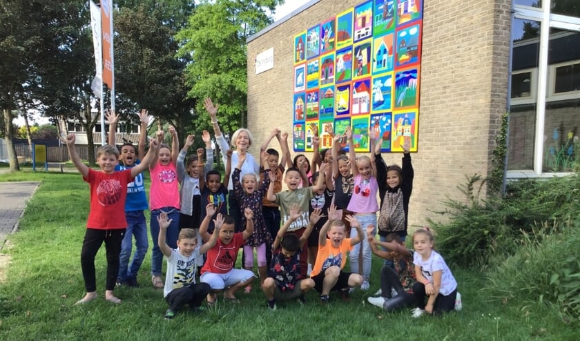 Anneke met een aantal leerlingen voor het prachtige kunstwerk van de kinderen uit groep 5.