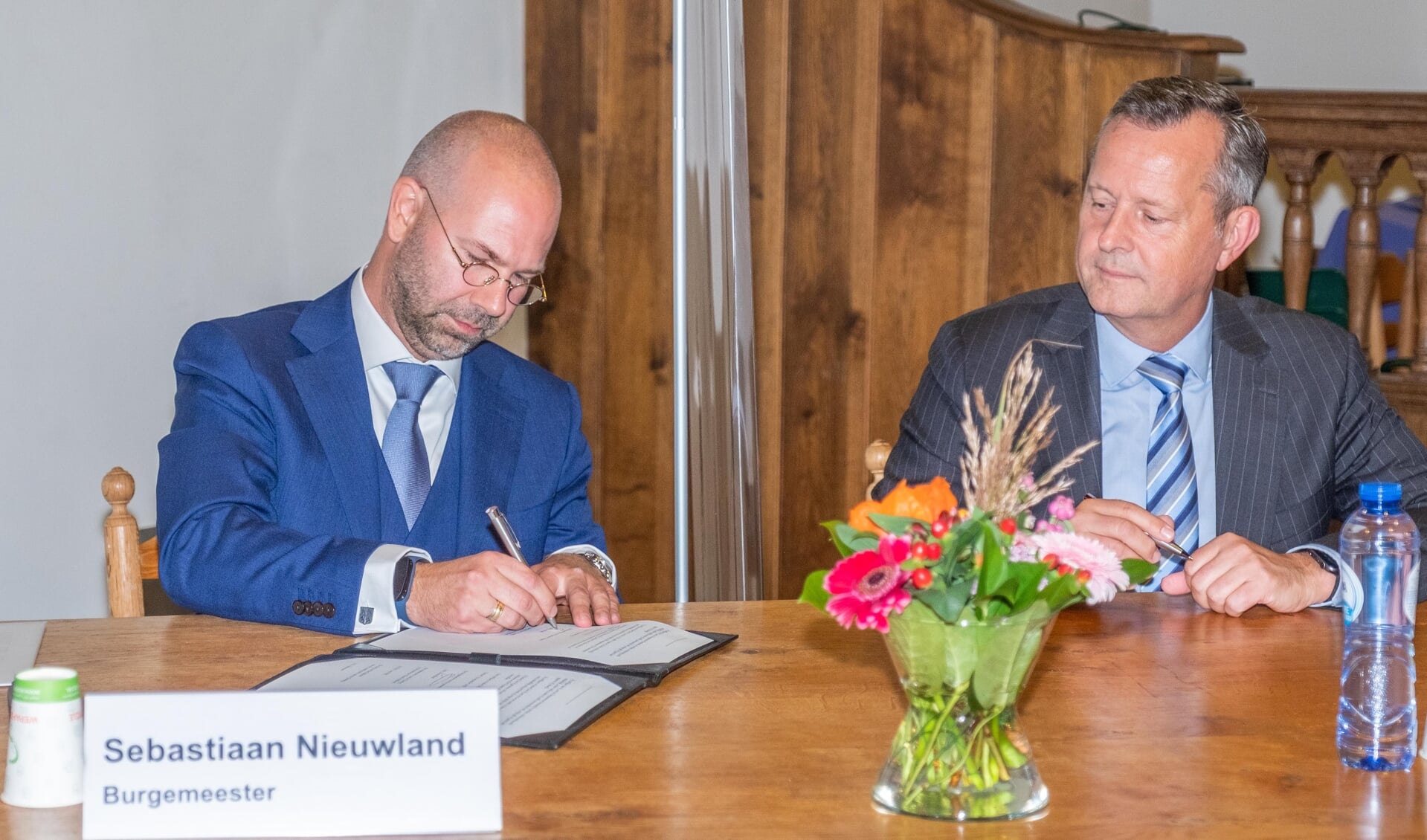 De ondertekening door burgemeester Nieuwland vindt plaats in het bijzijn van A. van Dijk (commissaris van de Koning provincie NH).