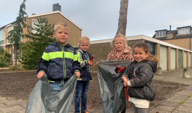 Kinderen van groep 1/2C van Kindcentrum De Kerkuil verzamelen zwerfafval rondom het schoolgebouw met behulp van afvalgrijpers.