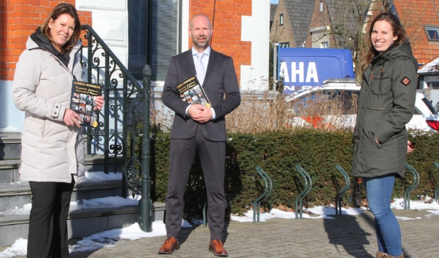 Burgemeester Nieuwland ontvangt het eerste exemplaar van het 'Horeca Kookboek' uit handen van initiatiefnemers Sylvia Blok (L.) en Nancy Floris.