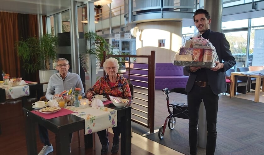 Ramon Wijker (rechts) komt namens Albert Heijn Limmen het valentijnspakket bezorgen. De heer en mevrouw Huijsmans zitten al klaar voor iets lekkers.
