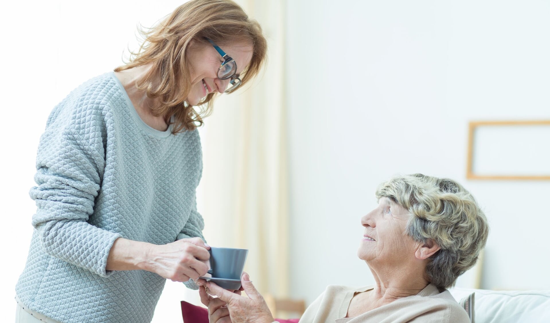 Smiling senior care assistant helping elderly lady