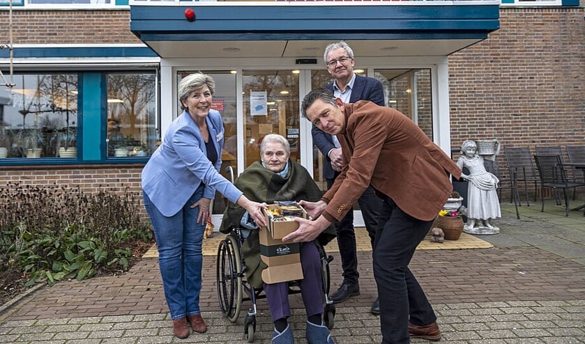 Alja Doorn, Elmer Ypenburg (managers ViVa! Zorggroep) en bewoonster Sjaantje Zonneveld (88) ontvangen het eerste winterpakket uit handen van wethouder Ron de Haan.   