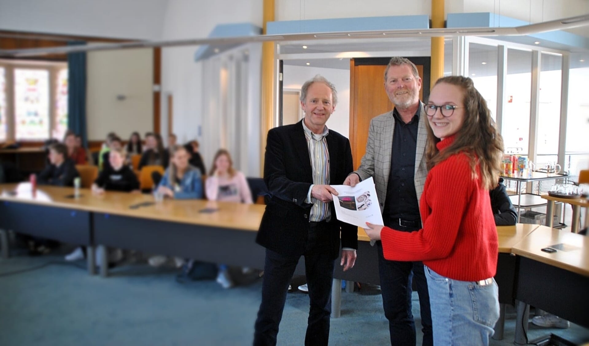 Op de foto vanaf links: Wethouders Jelle Brouwer (Uitgeest) en Peter van Diepen (Heiloo) overhandigen leerling Esther Min de opdracht om een mobiele werkplaats voor het basisonderwijs te ontwerpen.