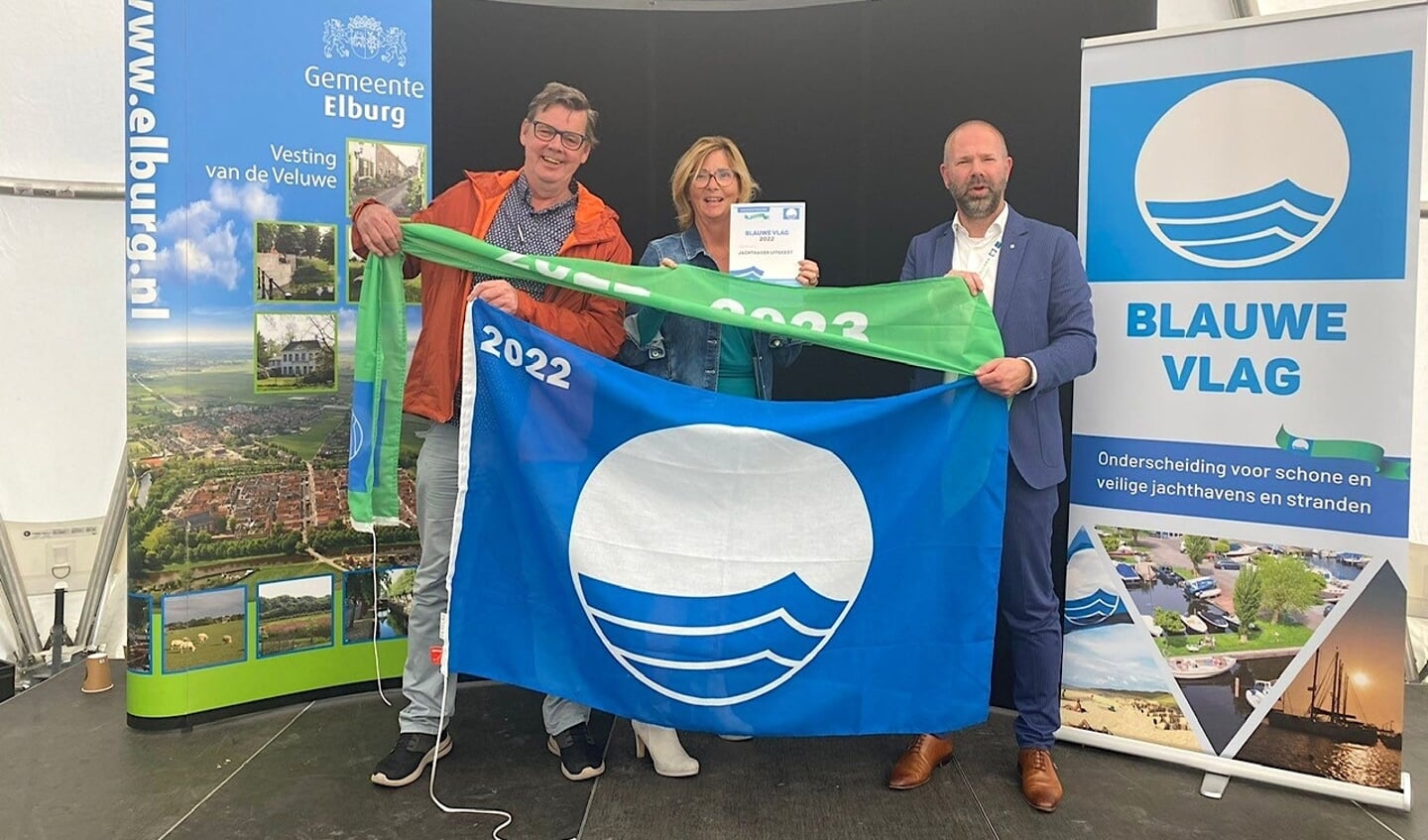 V.l.n.r. Menno en Caroline Klein-Bart en burgemeester Sebastiaan Nieuwland zijn trots op de uitgereikte Blauwe Vlag mét Groene Wimpel voor Jachthaven Uitgeest.