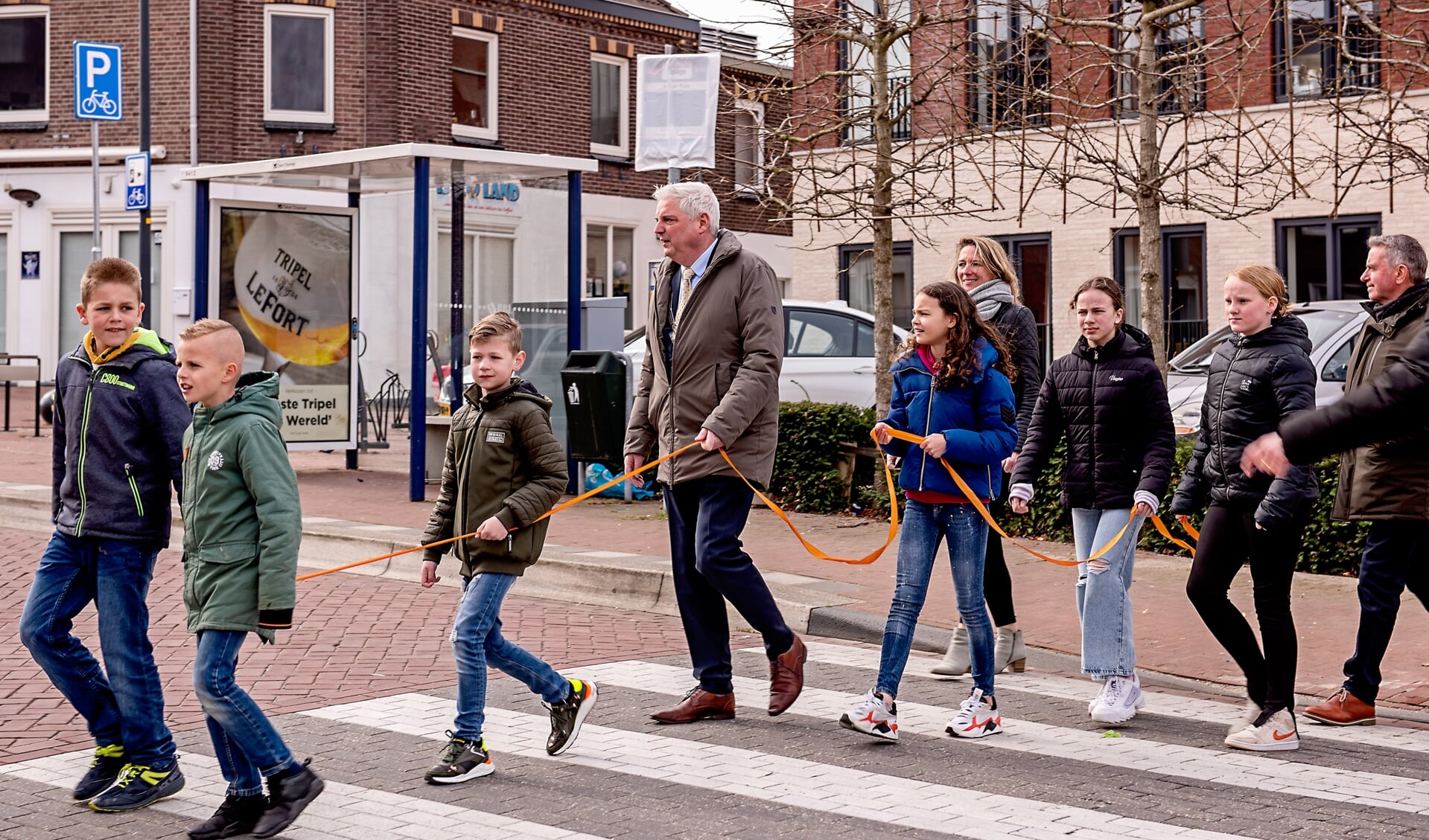 Burgemeester Eric Geurts wandelt samen met leerlingen van BS Schinveld de route van het wandelmuseum. Het oranje lint werd bij verzorgingstehuis Aan de Bleek doorgeknipt als openingshandeling.
