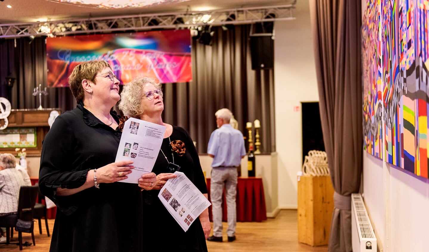 Bezoekers van de expositie, ter gelegenheid van het 75-jarig bestaan van Zangkoor Crescendo uit Doenrade, bekijken met interesse het kleurrijke vierluik van Paul Smeets.