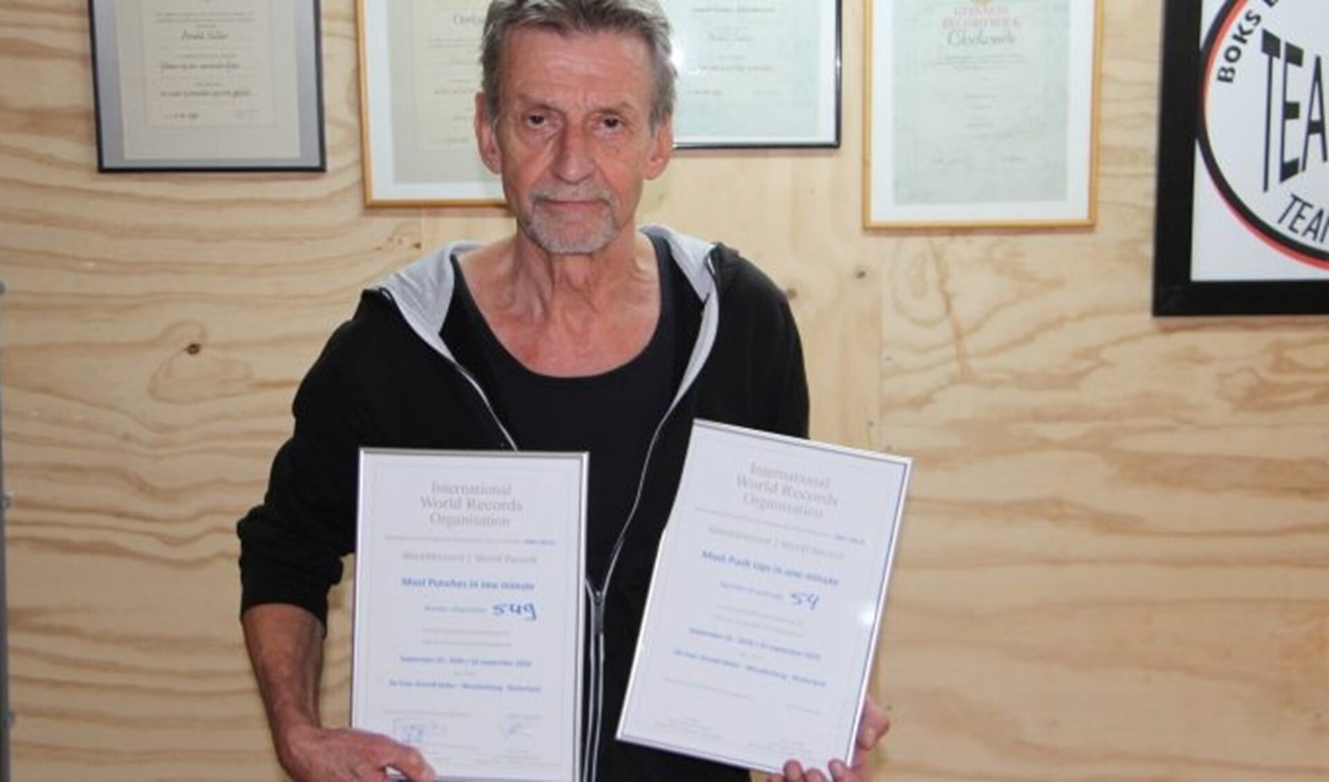 Vermoeid maar trots laat Arnold Keller de certificaten zien van de door hem zojuist behaalde Wereldrecords