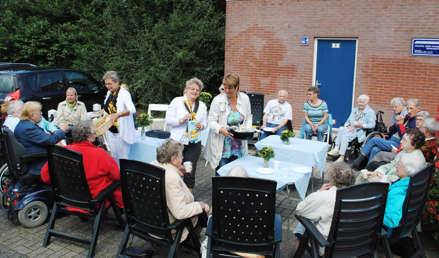 Een flinke groep ouderen geniet op het tijdelijke terras langs Smal Weesp 