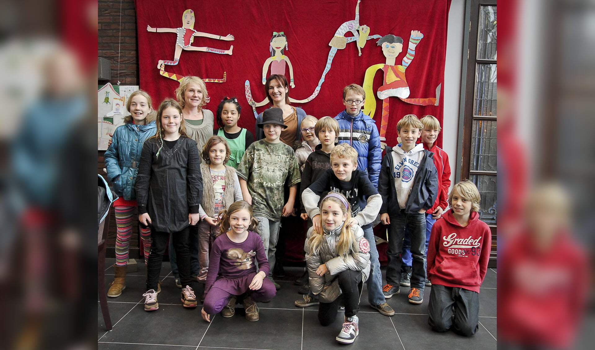 De leerlingen en docenten van Kunst & Knutsels, met op de achtergrond acrobaten van karton 