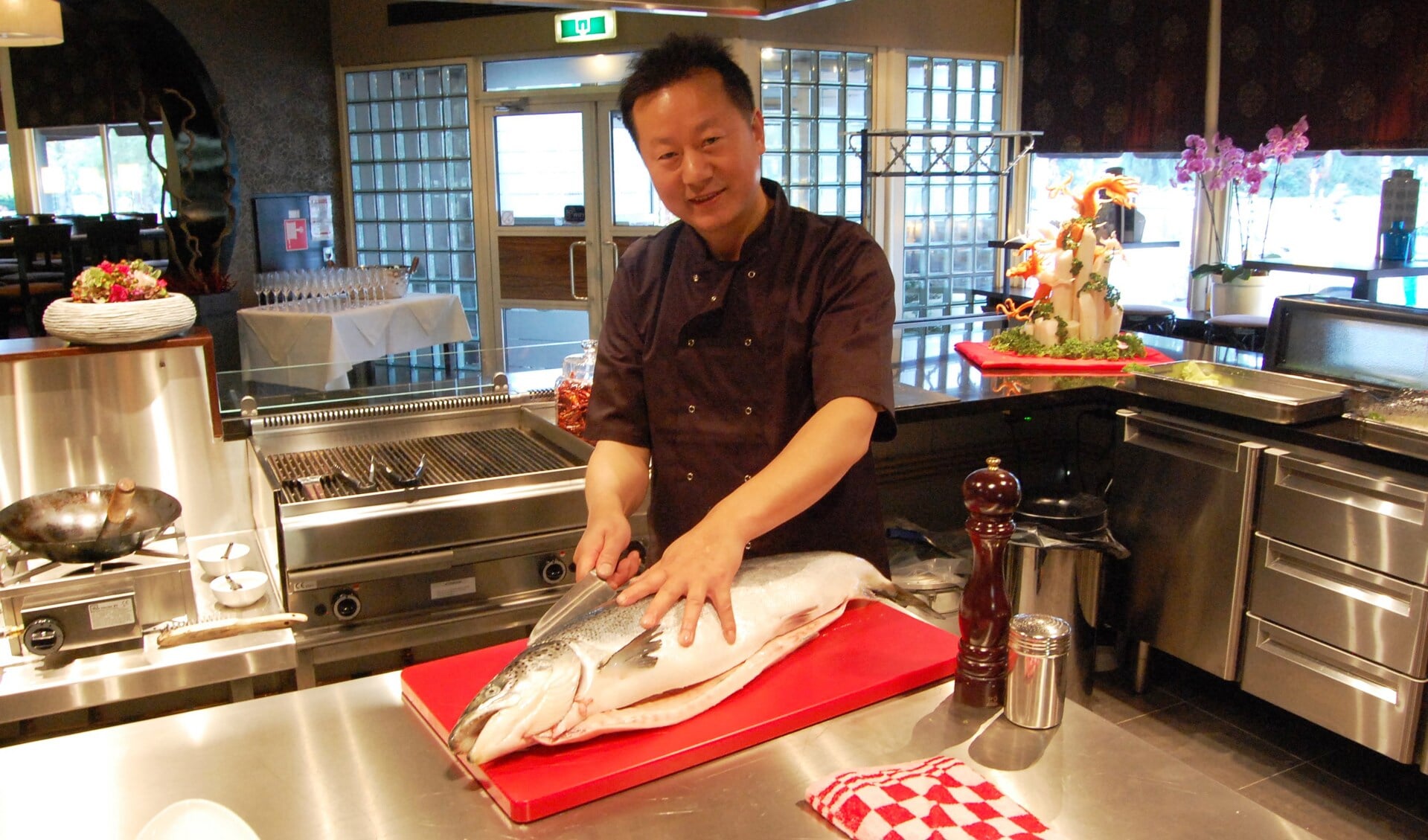Eigenaar Minsheng Hu fileert een verse zalm in zijn blinkendnieuwe keuken 
