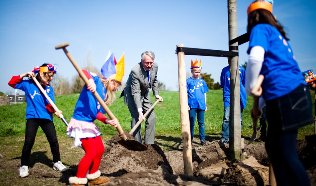 Kinderen en burgemeester planten boom.